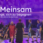 Das Bild zeigt den Titel "GEmeinsam - 100 Wege, sich zu begegnen" eines Tanztheaterstücks von und mit Bremer*innen. Im Hintergrund ist eine Gruppe von Menschen in Kostüm zu sehen, die sich auf einer großen Bühne begegnen.